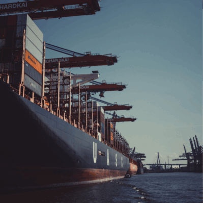 Containerschiff im Hafen mit großen Verladekränen am Kai.